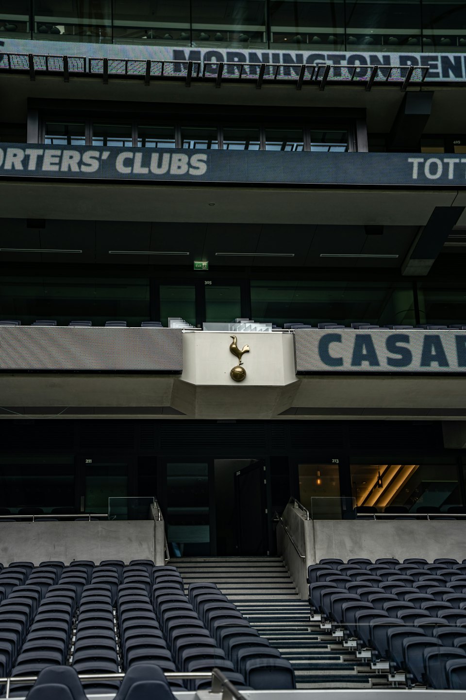 Empty sports stadium seating with large screens and club logo.